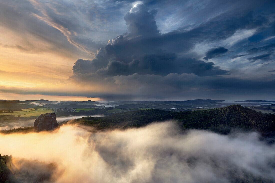 Impressive thunderstorm above the Saxon Switzerland national park with the Falkenstein in the evening sun and fog in the valleys, Saxony, Germany