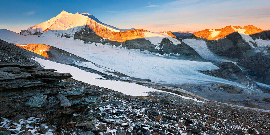 Blick vom Barrhorn auf den Sonnenaufgang über dem Brunegggletscher und den Gipfeln der Weißhorngruppe im Herbst, Wallis, Schweiz