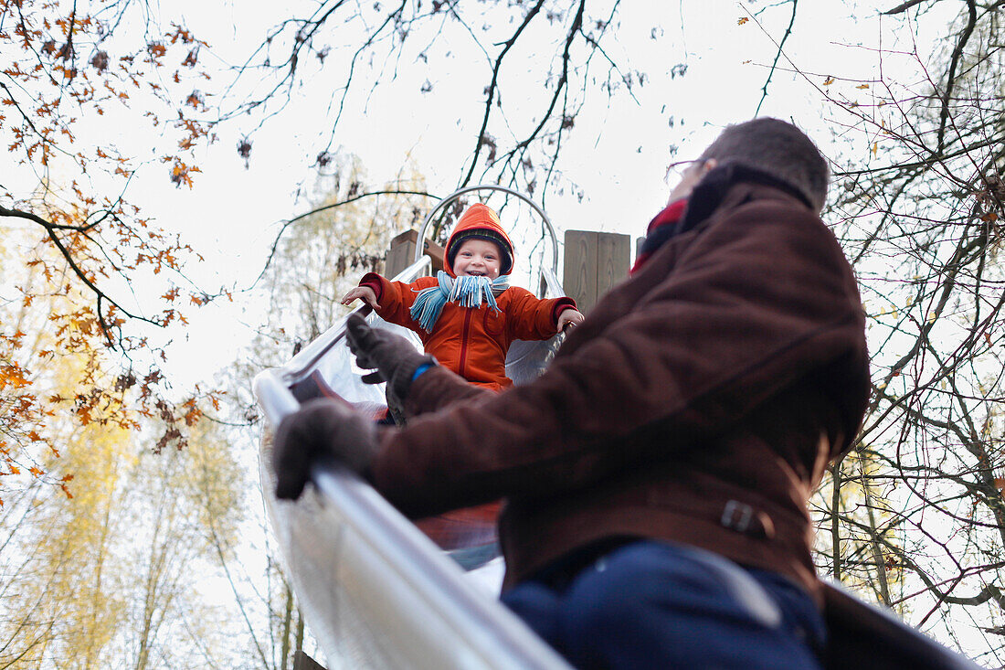 Father and son playing on a slide, Bad Oeynhausen, North Rhine-Westphalia, Germany