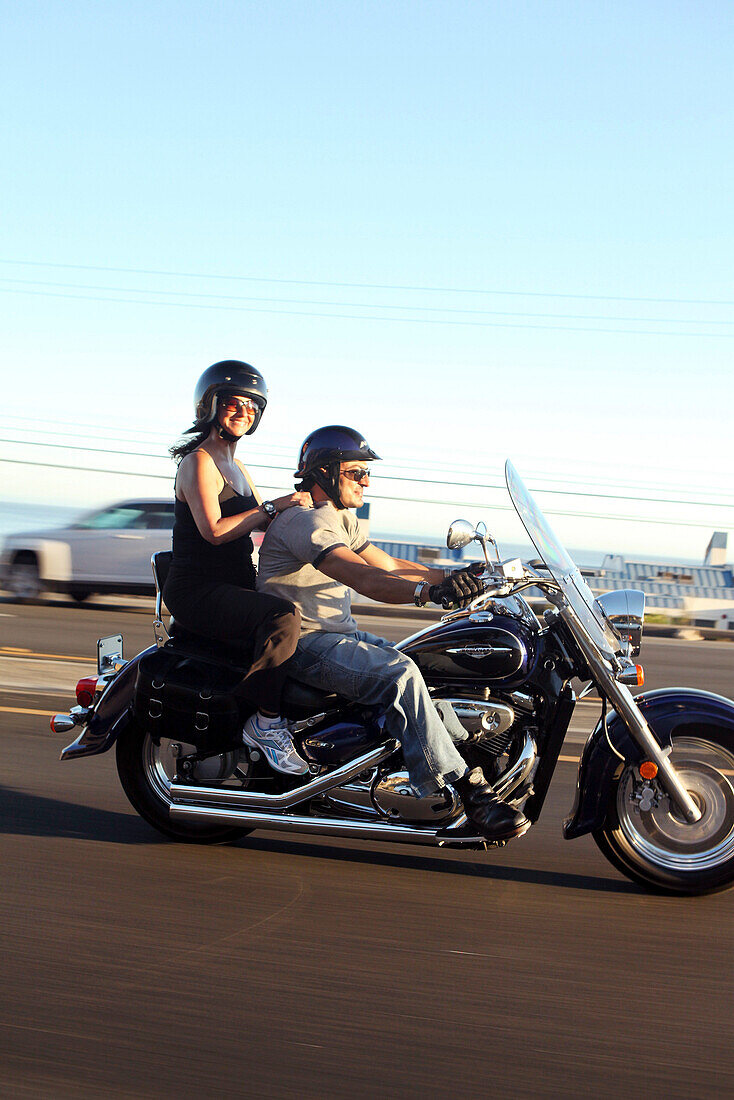 USA, California, Malibu, a couple on a motorcycle cruises along the Pacific Coast Highway at the end of the day