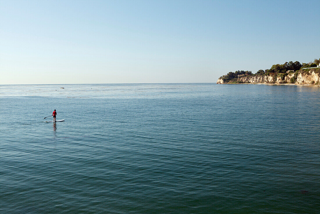 USA, California, Malibu, a man paddleboards in Paradise Cove, a view to the North