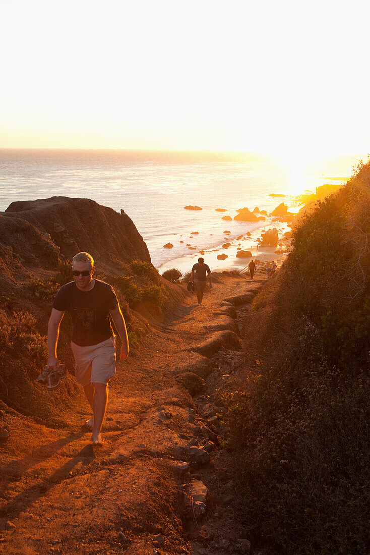 USA, California, Malibu, people walk up a trail from El Matador beach at sunset