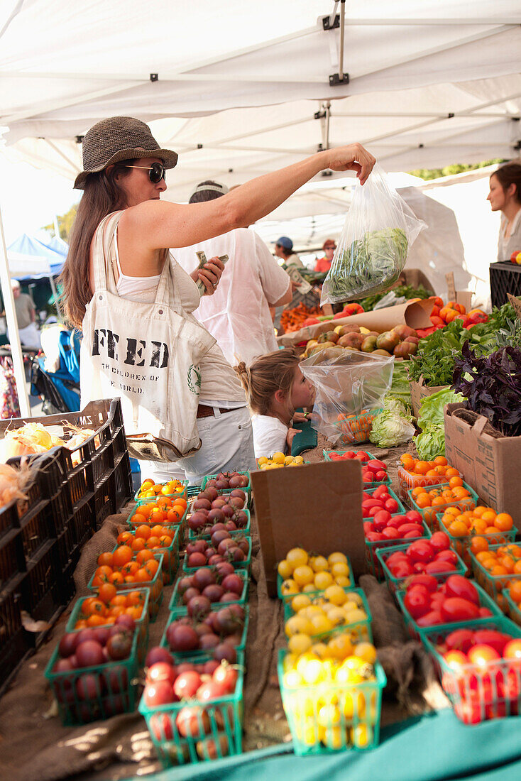 USA, California, Malibu, a woman buys produce at the Malibu farmers market on Civic Center Way