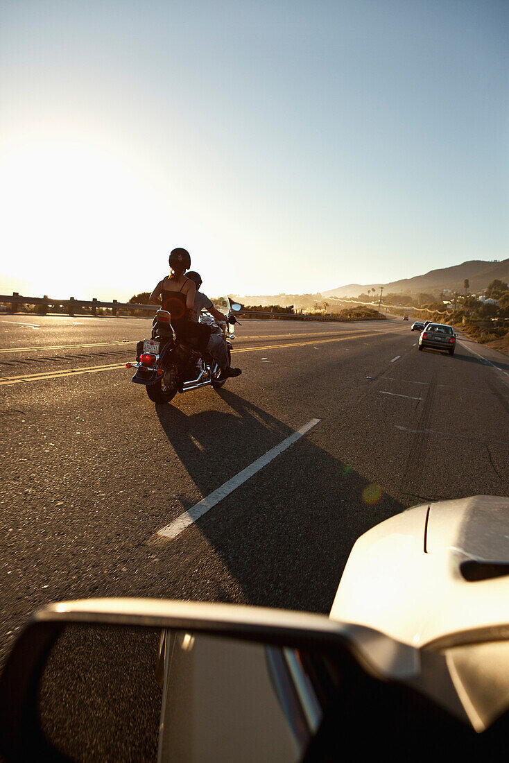 USA, California, Malibu, a couple on a motorcycle cruises along the Pacific Coast Highway at the end of the day
