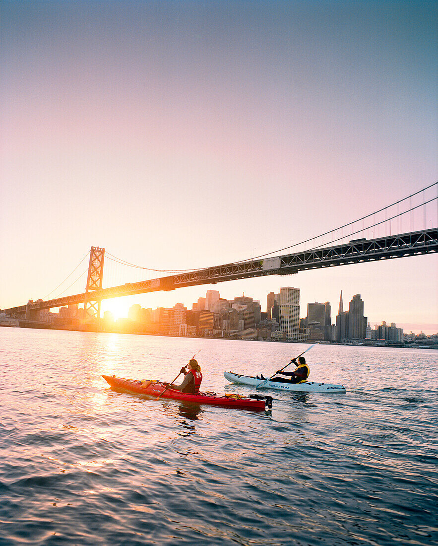 USA, California, San Francisco, a man and woman kayak in the San Francisco Bay under the Bay Bridge, the city of San Francisco in the distance