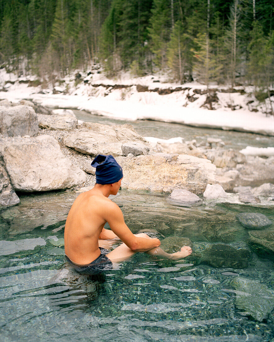 CANADA, man sitting in Lussier Hot Springs by river