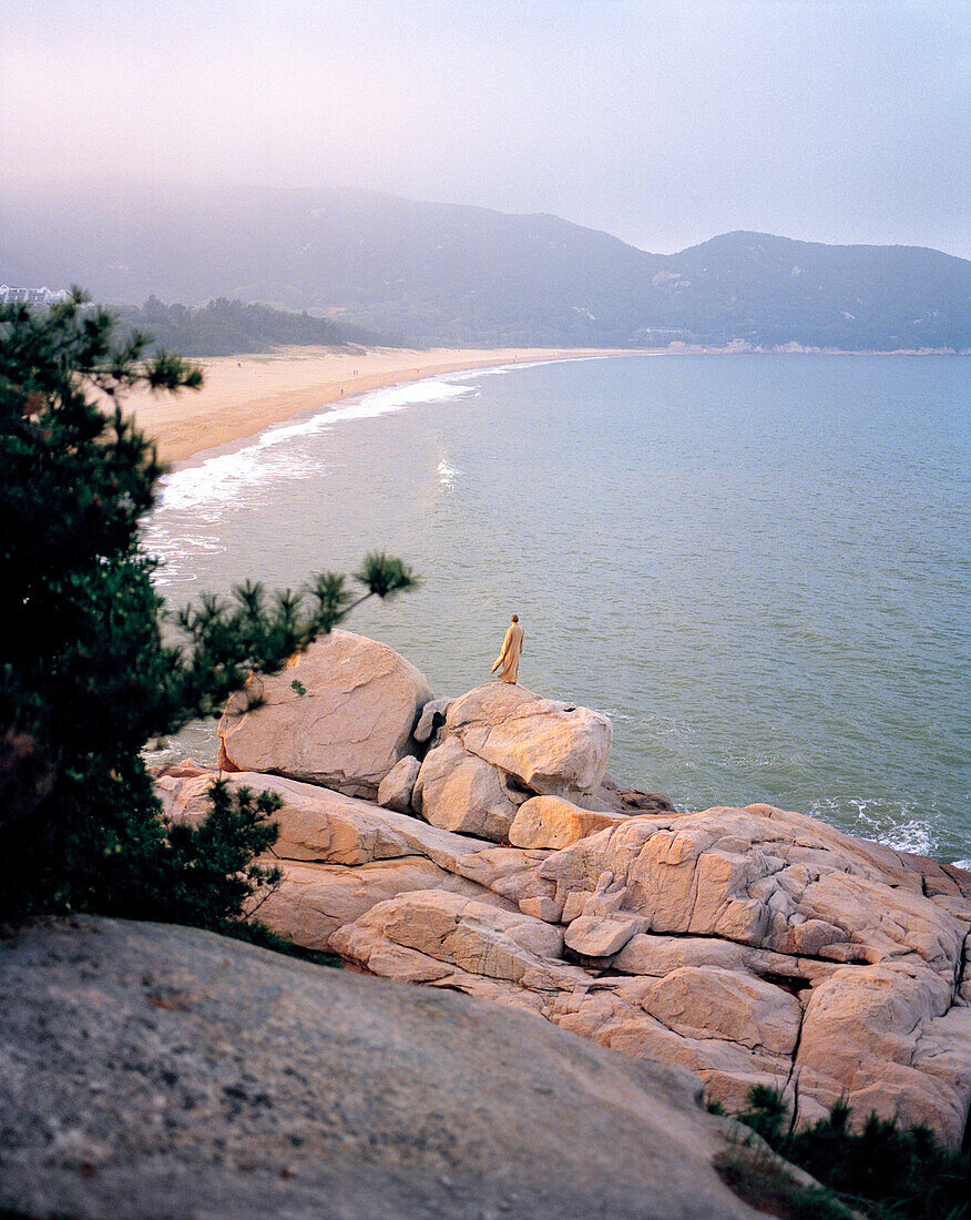 CHINA, elevated view of monk standing on the rock in front the East China Sea, Putuoshan