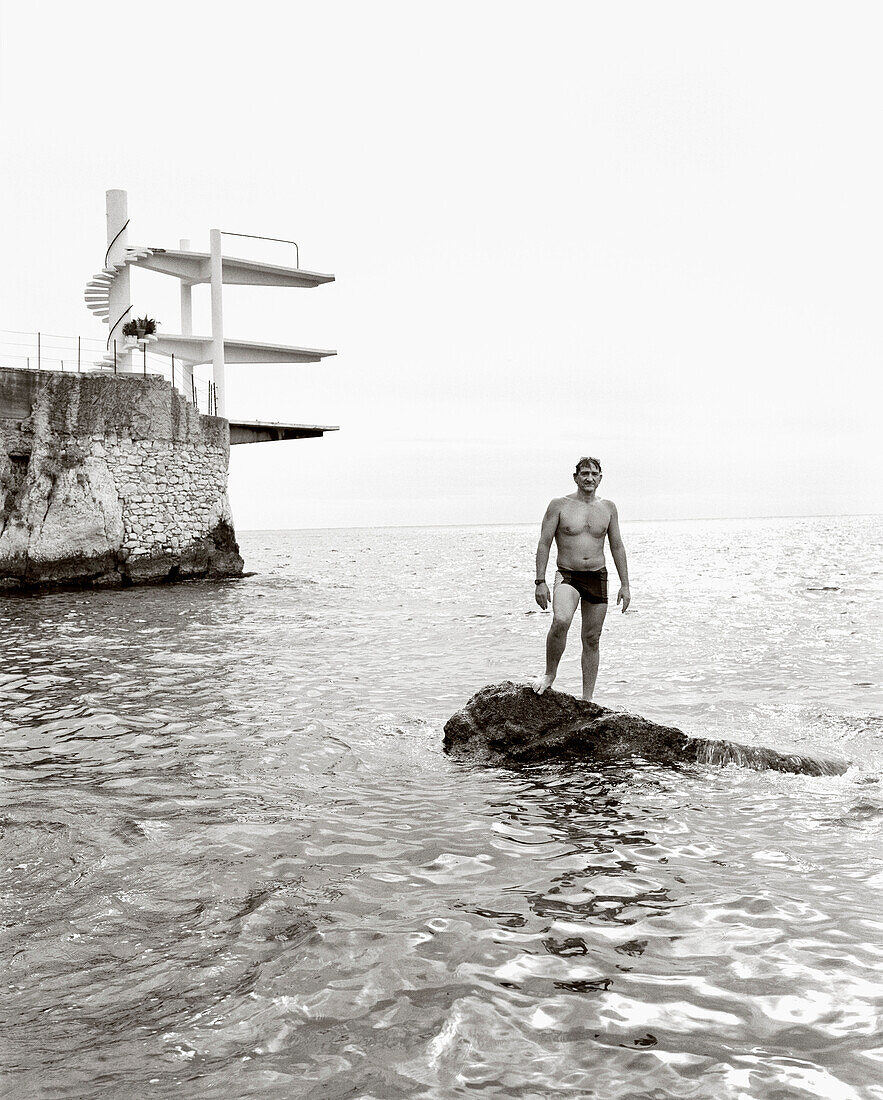 FRANCE, swimmer standing on rock in the Mediterranean Sea, Nice