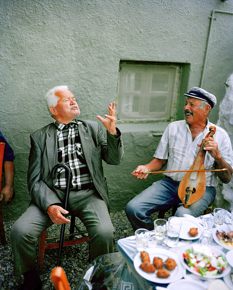 GREECE, Patmos Island, Michalis playing the lyra and while his friend sings at Diakofti Taverna, Early Afternoon