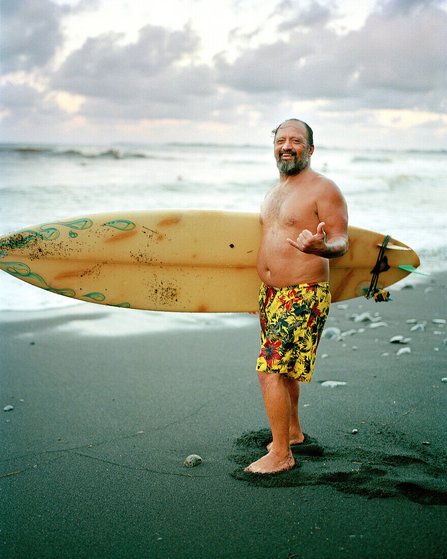 USA, Hawaii, portrait of senior surfer giving the hang loose, The Big Island, Honoli'i Beach