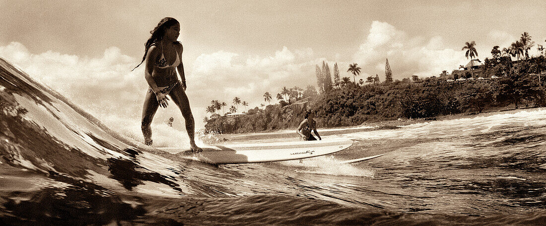 USA, Hawaii, Hilo, girls surf on a wave at Honoli'i beach, The Big Island (B&W)