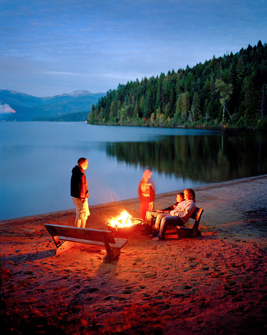 USA, Idaho, friends standing by a bonfire at Priest lake