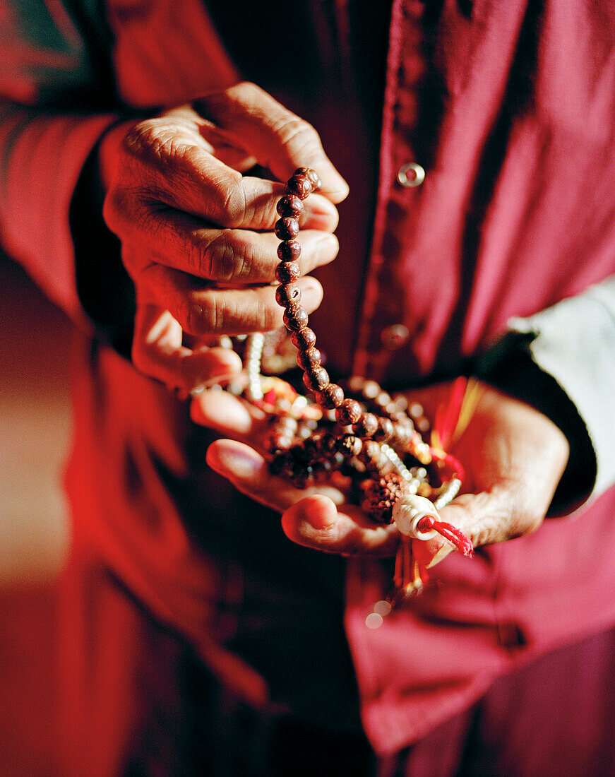 INDIA, West Bengal, midsection of lama holding string of beads, Kunsangnamdoling Monastery
