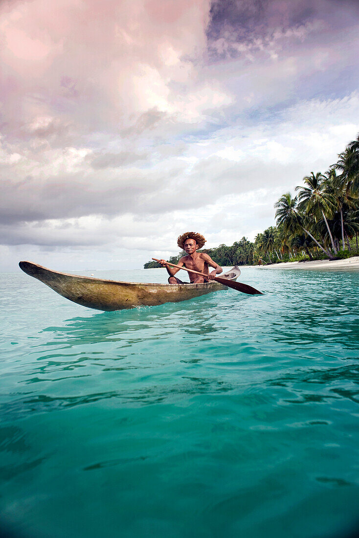 INDONESIA, Mentawai Islands, Kandui Resort, fisherman Gesayas Ges paddling his dugout canoe