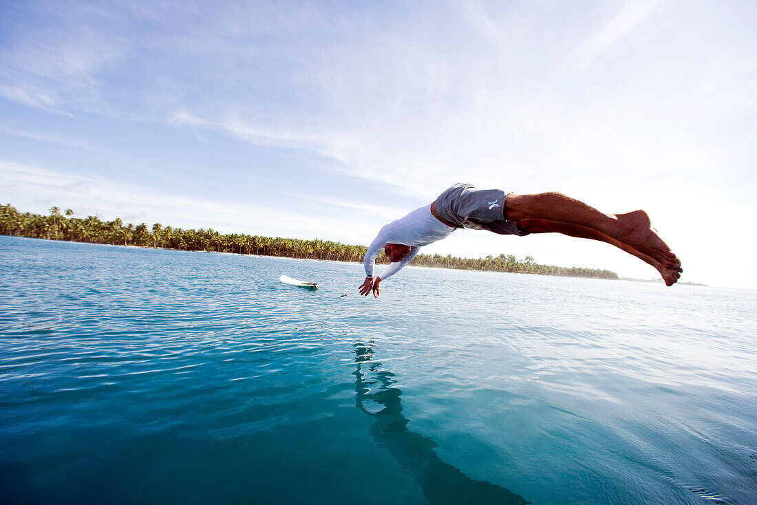 INDONESIA, Mentawai Islands, Kandui Resort, surfer diving into the water to go surfing, Nipussi