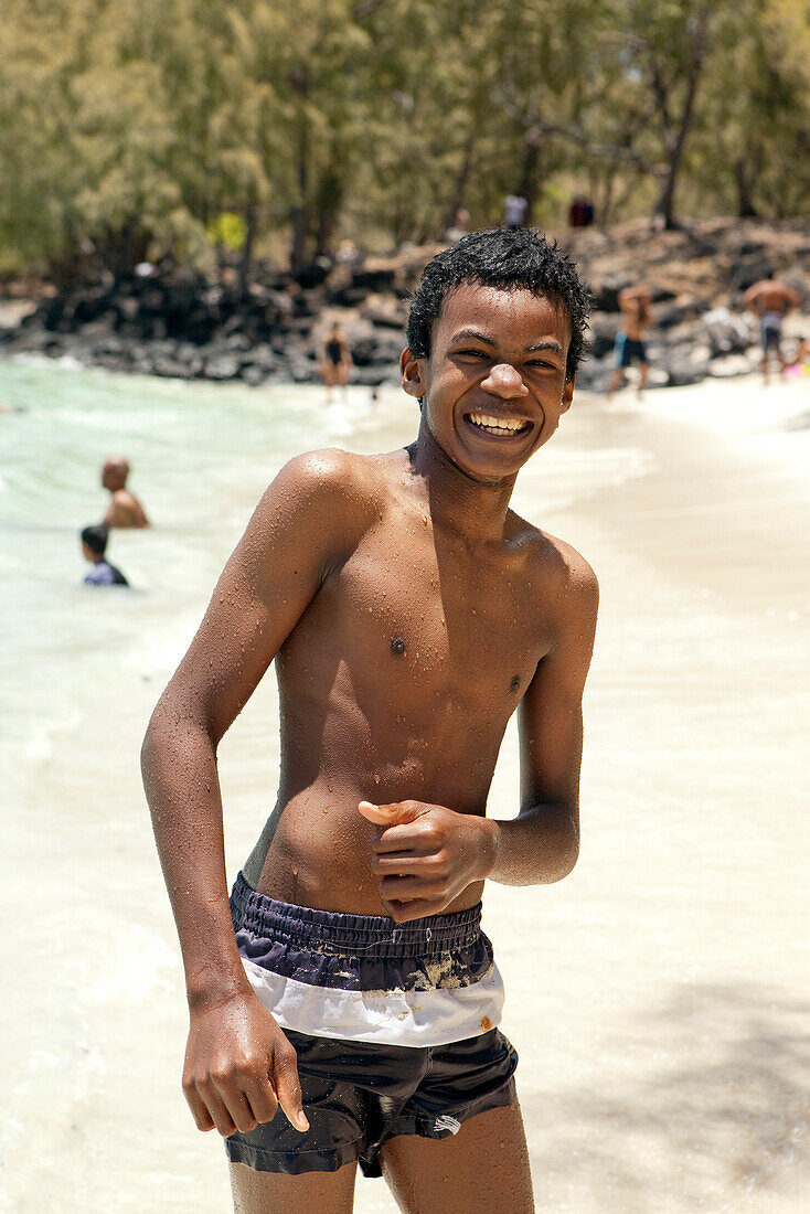 MAURITIUS, a boy smiles on the beach at Ile aux Cerfs Island, Indian Ocean