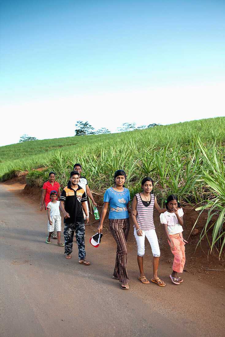 MAURITIUS, Chamarel, a family walks down the road after a visit to see Seven Coloured Earth, a geological formation that was the first tourist attraction in Mauritius