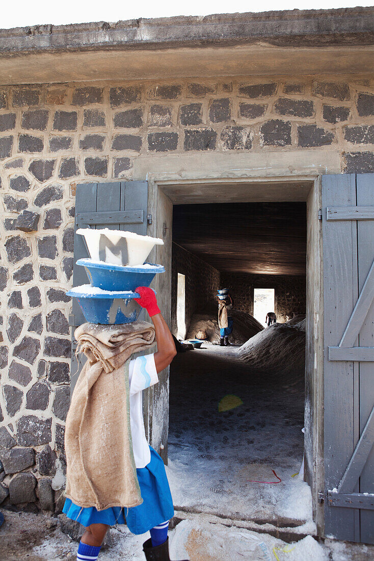 MAURITIUS, Tamarin, women carry heavy loads of salt to a storage facility where it is stored and prepared for transportation, Tamarin Salt Pans