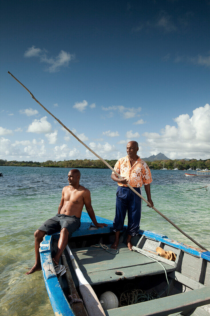 MAURITIUS, Trou D'eau Deuce, fisherman Rolau Dardenne 80 and his grandson Kelvin Dardenne in their boat, preparing to go fishing off of the East coast of Mauritius, Indian Ocean, 4 Sisters Mountain in the distance