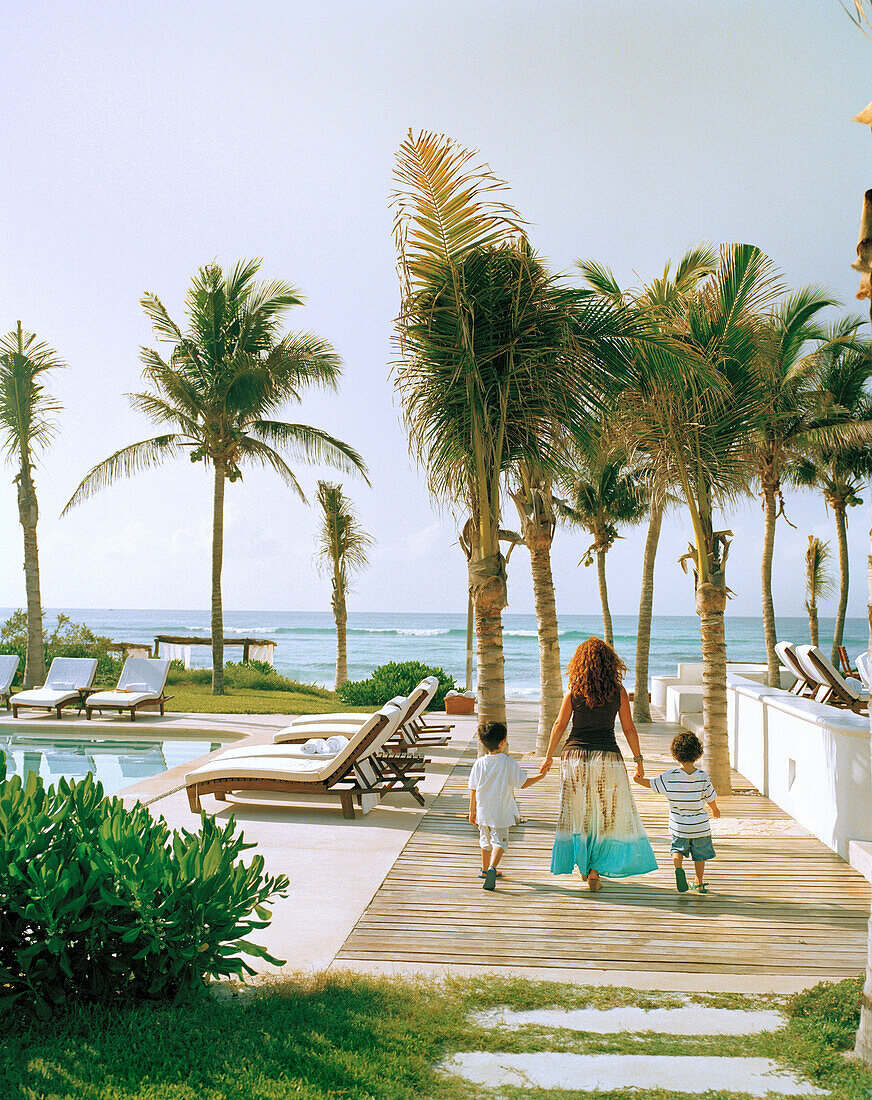 MEXICO, Maya Riviera, mother and sons walking by a swimming pool, Esencia Hotel and Villas