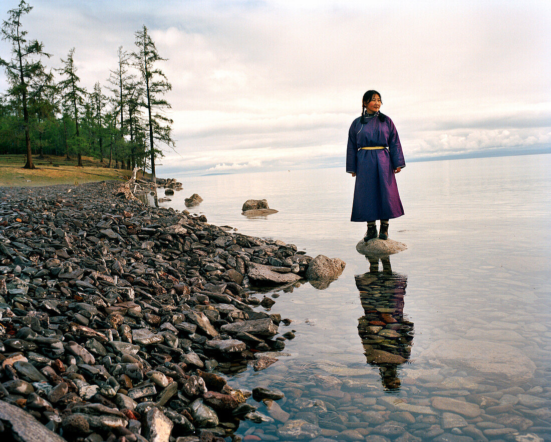 MONGOLIA, Khuvsgul National Park, the dark blue pearl, a woman stands on a rocky by the shore of Lake Khuvsgul, Toilogt Ger Camp