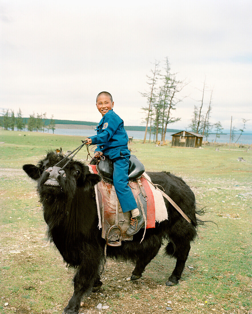 MONGOLIA, Batkhuu's home near Khuvsgul Lake, portrait of a smiling boy riding a yak, Khuvsgul National Park