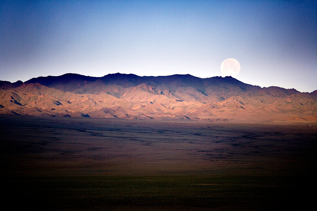 MONGOLIA, Gobi Desert, barren landscape under the setting full moon in the morning