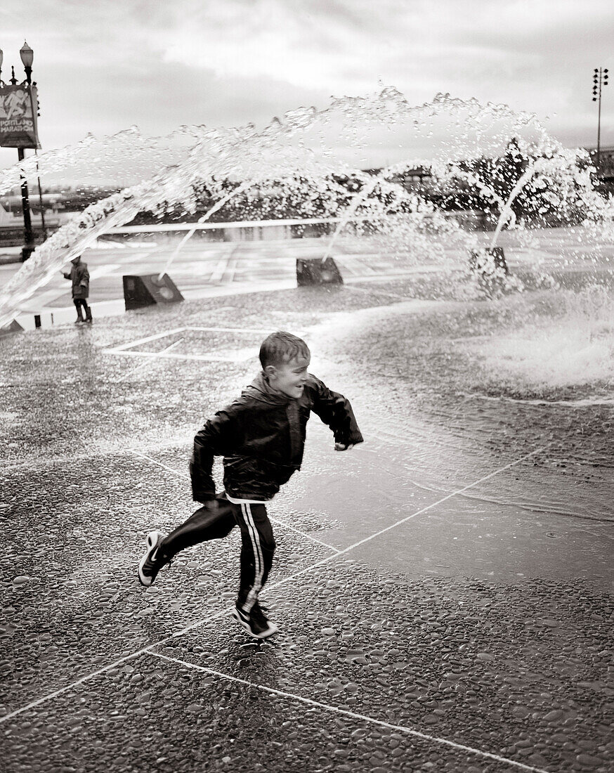 USA, Oregon, Portland, boy running in fountains (B&W)