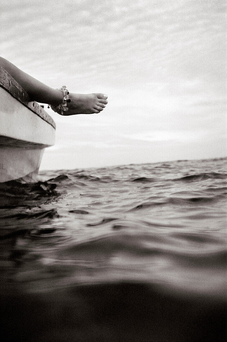 PANAMA, Bocas del Toro, a woman relaxes and hangs her foot off the side of a boat, Central America (B&W)