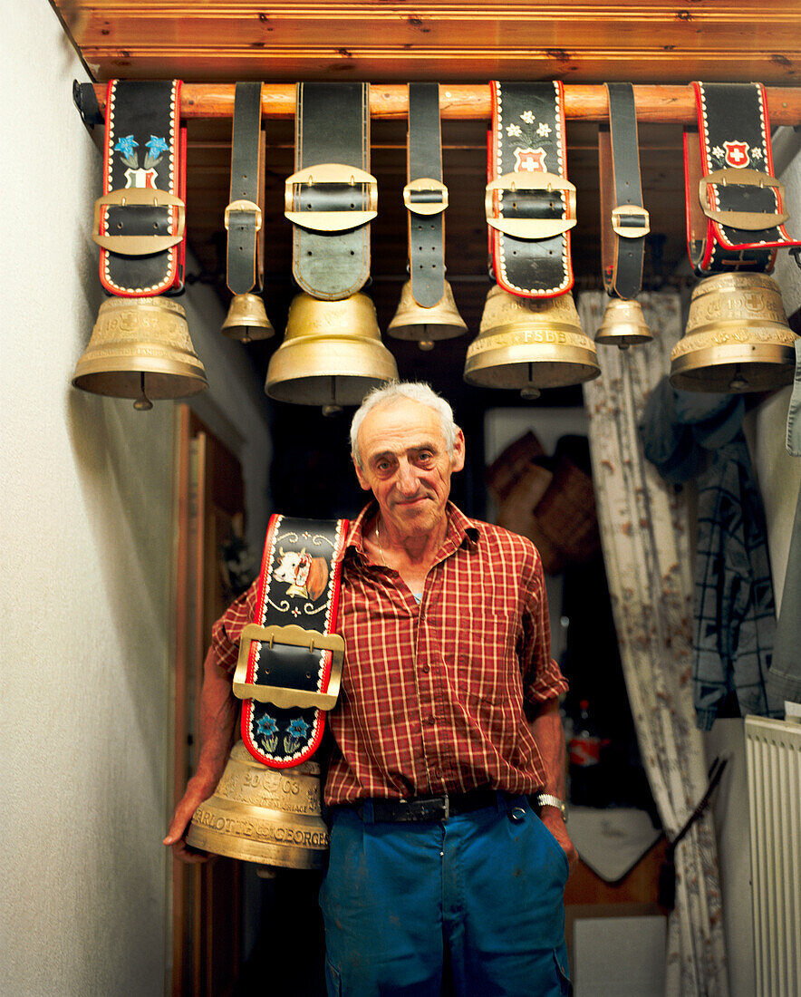 SWITZERLAND, Motiers, George Montandon stands in the kitchen of his home holding a cow bell that was given to him by a friend for his 45th wedding anniversary, Jura Region