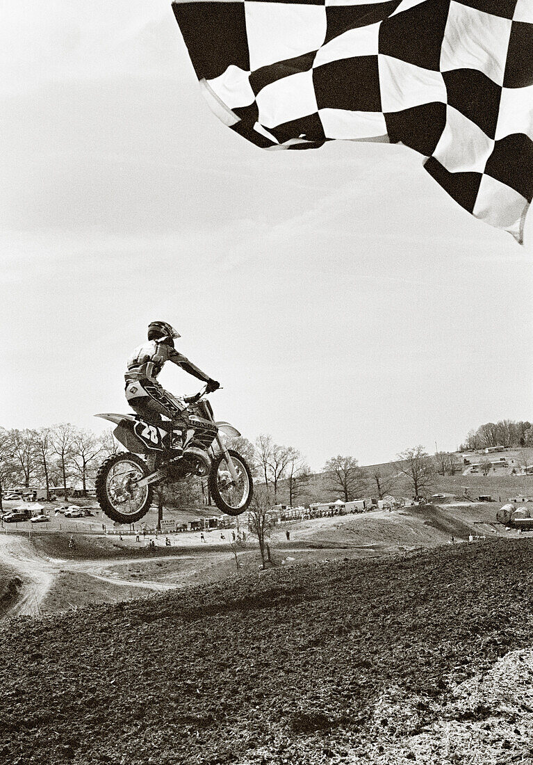 USA, Tennessee, motocross winner jumping across the finish line (B&W)