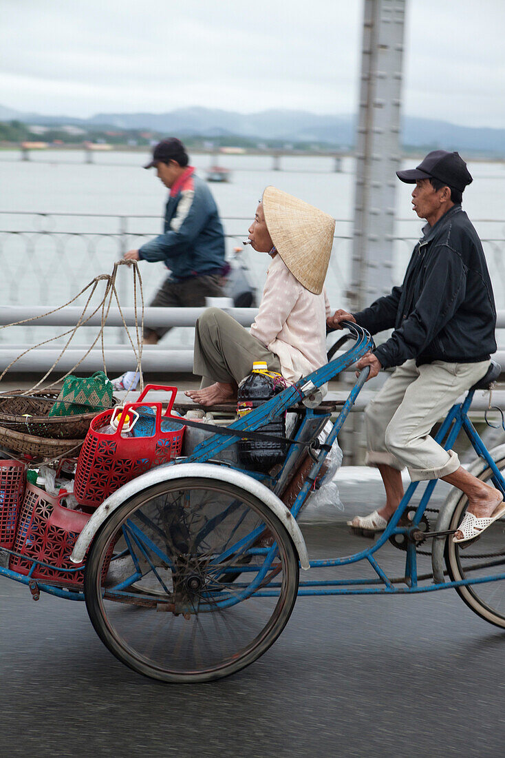 VIETNAM, Hue, a food vendor bicycles his wife across the Perfume river in the early morning