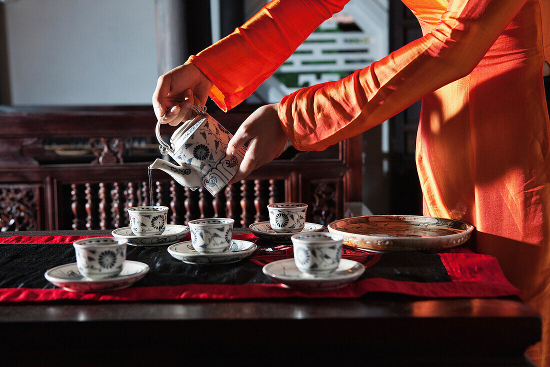 VIETNAM, Hue, Ms. Boi Tran's Hoang Vien restaurant, a woman in traditional dress pours tea