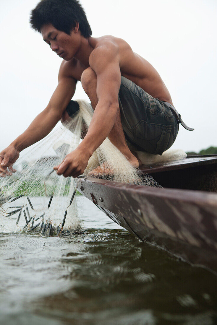 VIETNAM, Hue, Perfume river, fisherman Tran Van Son with his casting net in his Sampan boat, La Y Village, Phu Vang District, Thua Thien Hue Province