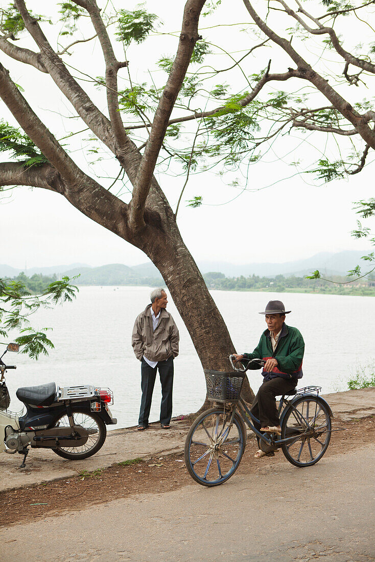 VIETNAM, Hue, a man rides his bike next to the Perfume River