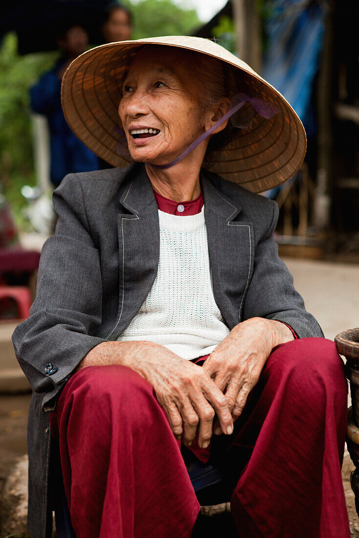 VIETNAM, Hue, an elderly woman sells peanuts outside in front of an old monastery