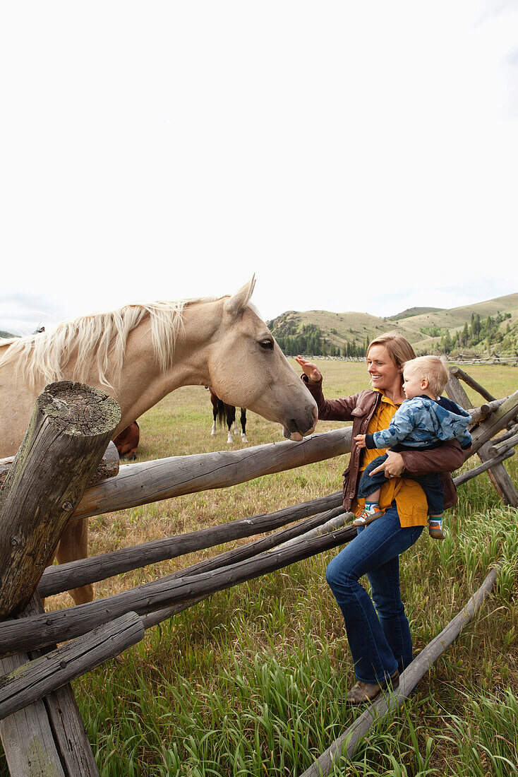 USA, Wyoming, Encampment, a woman and her son pet a horse on the nose, Abara Ranch