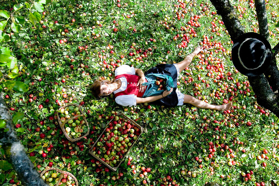 Frau liegt unter einem Apfelbaum, Steiermark, Österreich