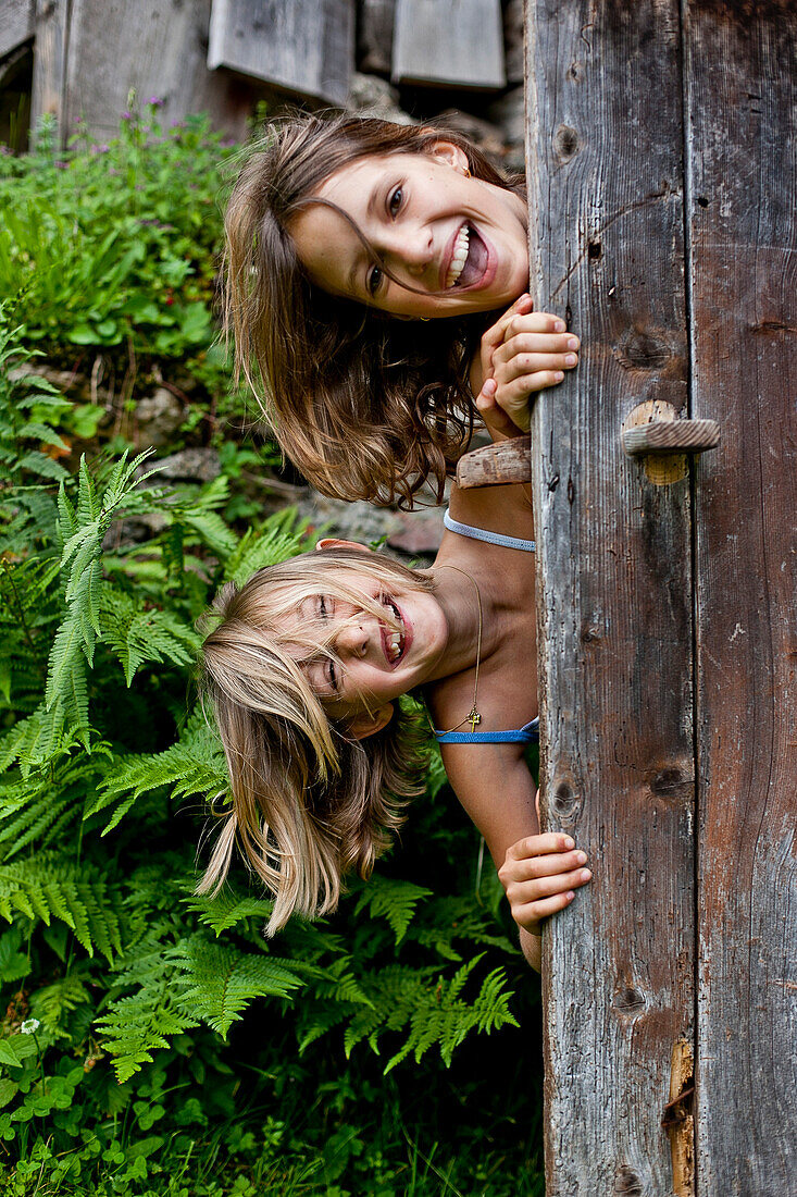 Two girls behind an old wooden door, Styria, Austria