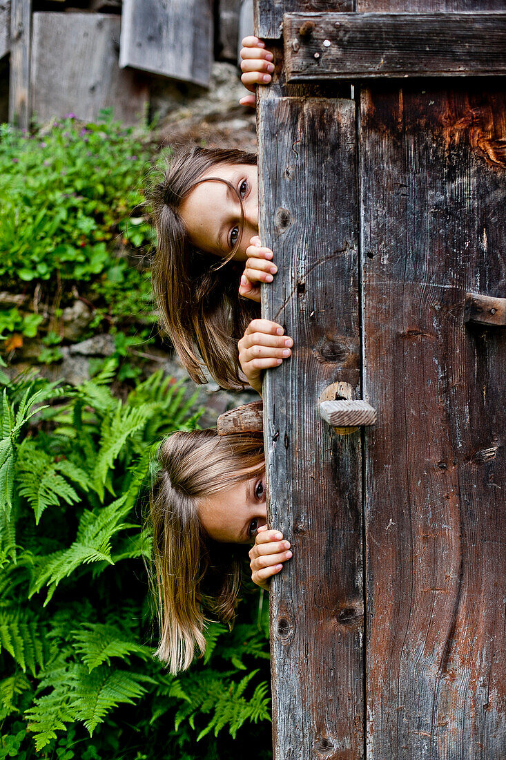 Two girls behind an old wooden door, Styria, Austria