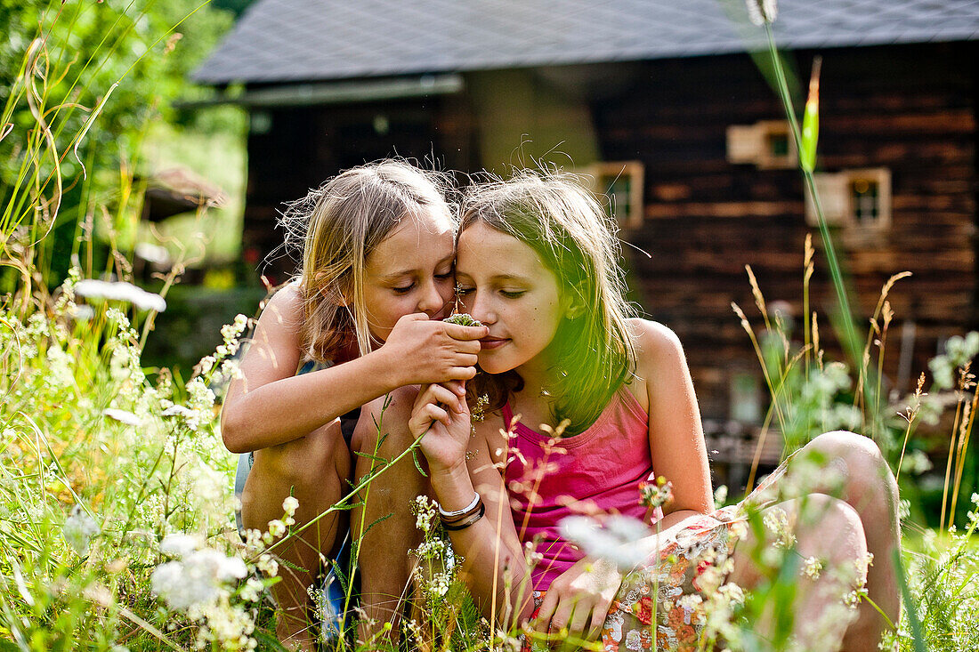 Two girls smelling a flower, Styria, Austria