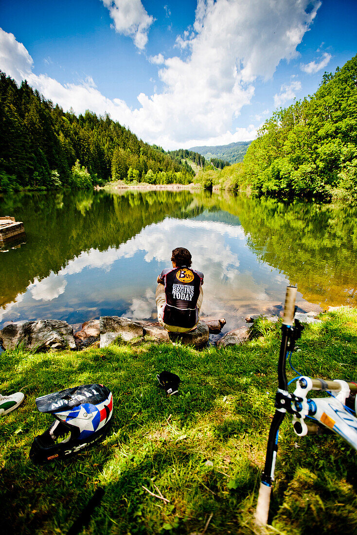 Mountain biker resting at pond Leonharditeich, Murau, Styria, Austria
