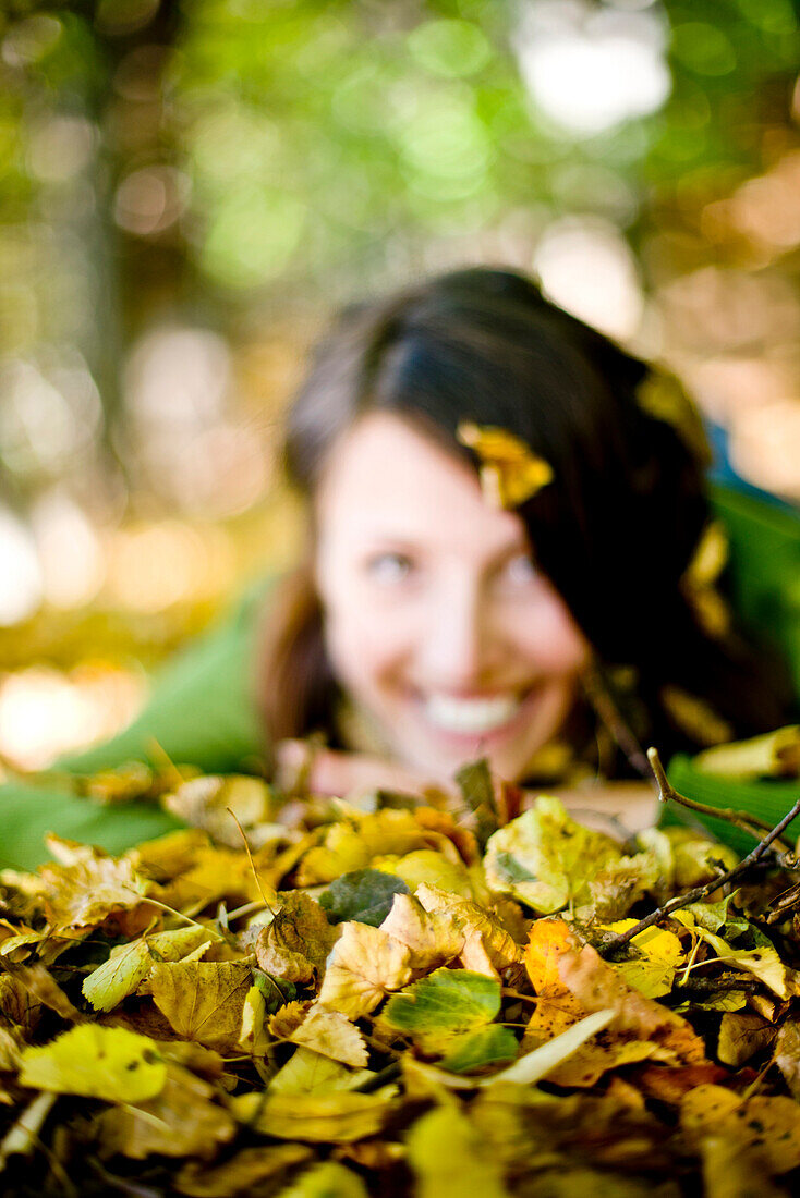 Young woman lying in autumn leaves, Styria, Austria