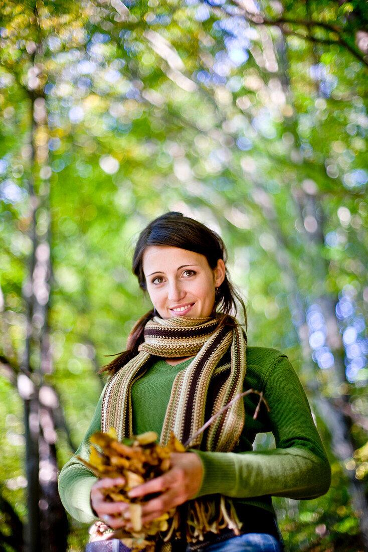 Junge Frau hält Herbstlaub in den Händen, Steiermark, Österreich