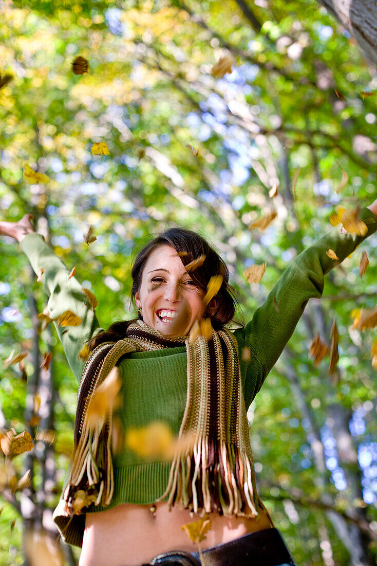 Young woman throwing autumn leaves in the air, Styria, Austria