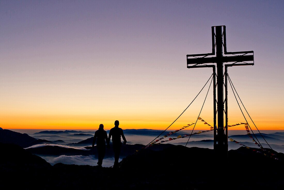 Two hikers at summit of Hochschwab mountain at sunrise, Hochschwab, Styria, Austria