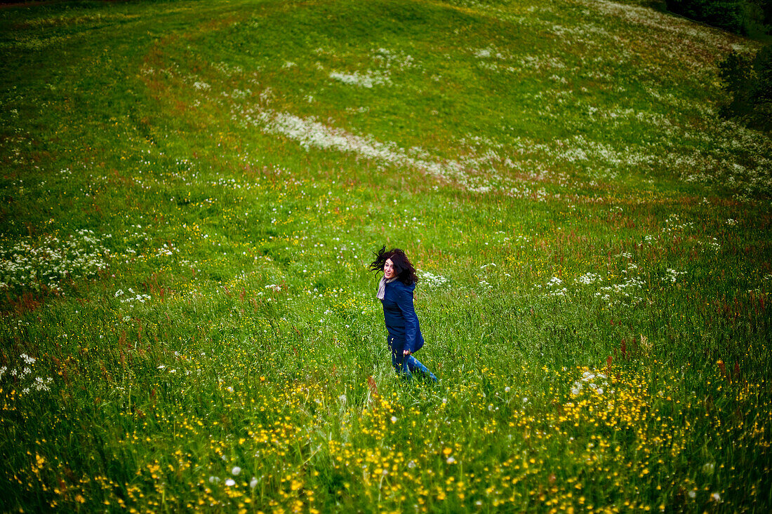 Frau läuft über eine Blumenwiese, Steiermark, Österreich