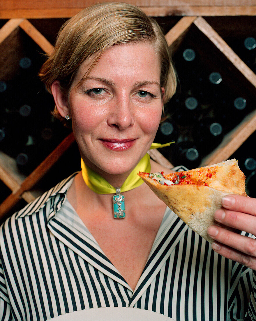 USA, California, Los Angeles, portrait of a mid adult lady holding pizza at Pizzeria Mozza.