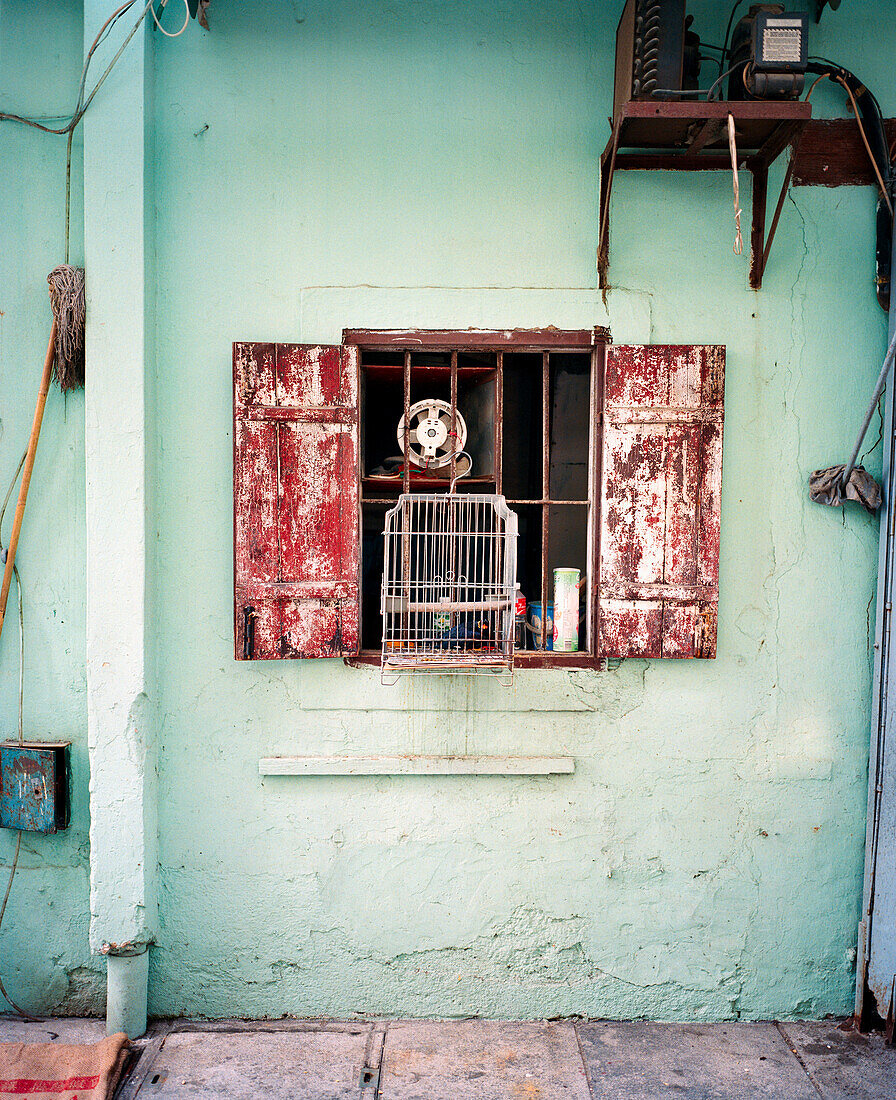 CHINA, Macau, Birdcage hanging in front of house window