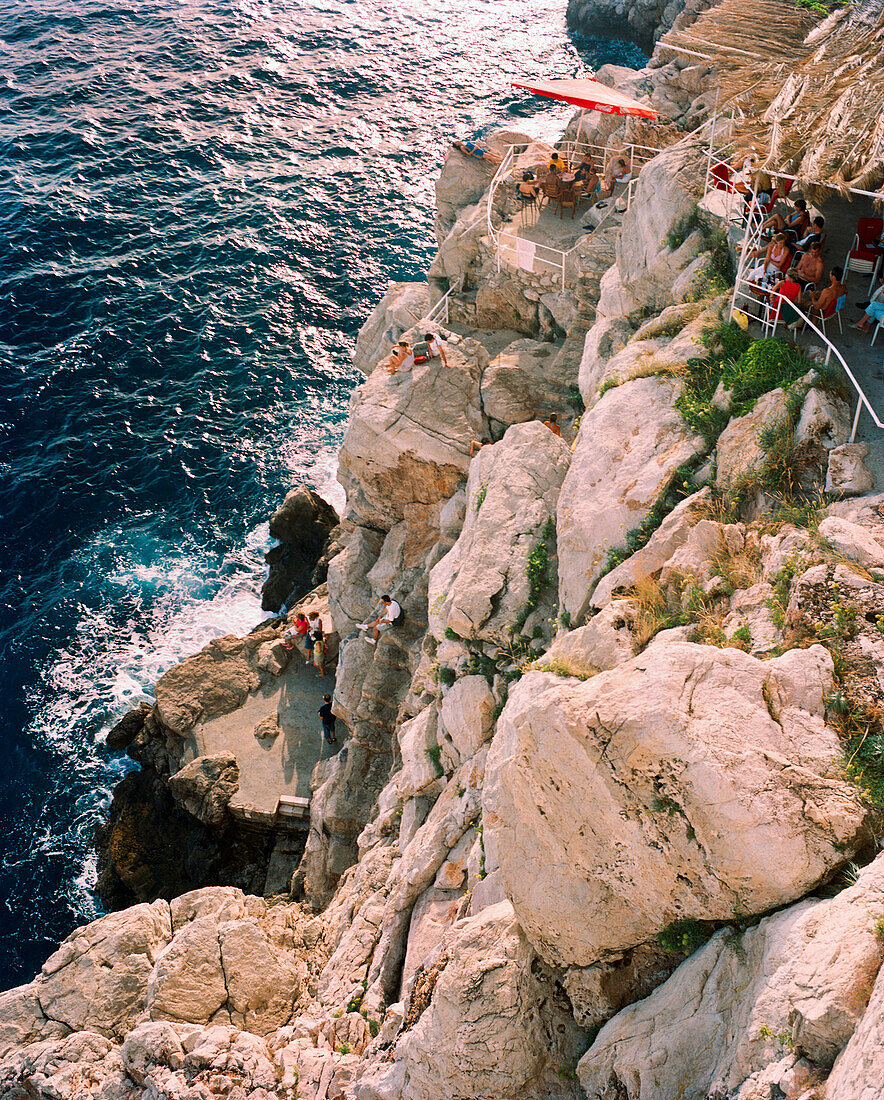 CROATIA, Dubrovnik, Dalmatian coast, the Buza Bar at the edge of the cliff with guests sitting to watch the sunset.